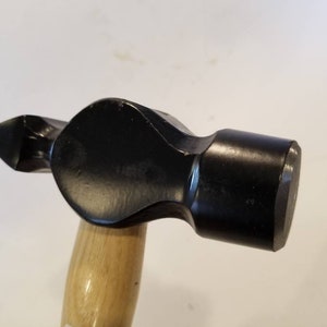 May include: A black hammer with a wooden handle. The hammer has a rounded head and a flat striking surface.