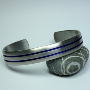 Solid hand crafted convex shaped titanium bangle bracelet with blue anodized grooves. Titanium jewelry. Mens bracelet. Mens jewelry.