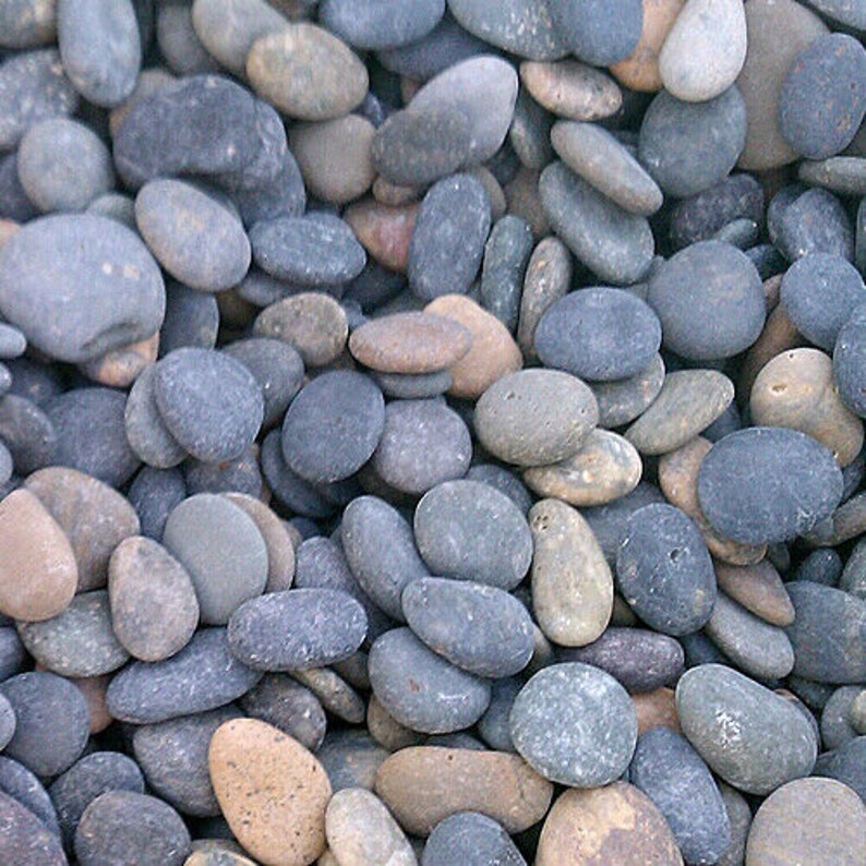 May include: A close-up of a collection of smooth, grey and brown river rocks. The rocks are various sizes and shapes, and they are arranged in a random pattern.