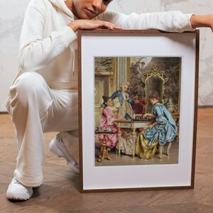Man holding the framed Rococo chess painting print; frame not included.