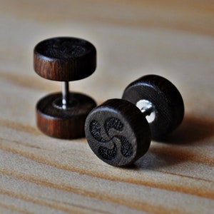 May include: A pair of dark brown wooden earrings with a black swirl design. The earrings are made of wood and have a silver post.