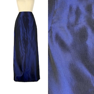 May include: A long, dark blue skirt made of a shiny, silky fabric. The skirt is fitted at the waist and flows down to the floor.