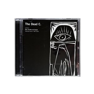 Op de afbeelding: Een cd-hoesje met een zwart-witte albumhoes. De tekst "The Dead C." staat bovenaan, met extra tekst eronder. De cover art bevat een gestileerd oog en geometrische vormen.