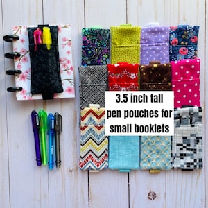 May include: A collection of 3.5-inch tall pen pouches in various patterns, including floral, polka dot, and geometric designs. The pouches are displayed with a small notebook and several pens. The text on the image reads: "3.5 inch tall pen pouches for small booklets."