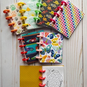 Pode incluir: Um conjunto de três canecas de cerâmica com um esmalte salpicado de cor creme. Cada caneca apresenta um design floral pintado à mão em tons de azul, verde e amarelo. As canecas têm uma forma simples e arredondada e uma alça.