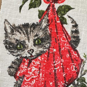 May include: Vintage fabric featuring a tabby kitten with green eyes, nestled in a red bandana tied to a branch with green leaves. The fabric has a calendar with the month of January visible.