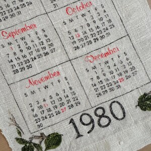 May include: Vintage 1980 calendar printed on a linen-like fabric. The calendar features months like September, October, November, and December, with dates in black and red. Floral accents are visible at the edges.