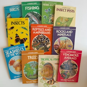 May include: A collection of eleven vintage A Golden Guide softcover books featuring various nature topics including Birds, Fishing, Herbs and Spices, Insect Pests, Insects, Reptiles and Amphibians, Rocks and Minerals, Seashells, Trees, Tropical Fish, and Venomous Animals.