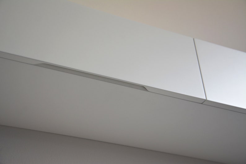 May include: White kitchen cabinets with a recessed handle.