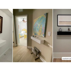 May include: Three different examples of floating shelves in a hallway. The first shelf is white and is mounted below a framed picture. The second shelf is white and is mounted below a colorful abstract painting. The third shelf is black and is mounted below a framed print of a landscape. The text "custom color & size" is visible in the bottom right corner of the image.