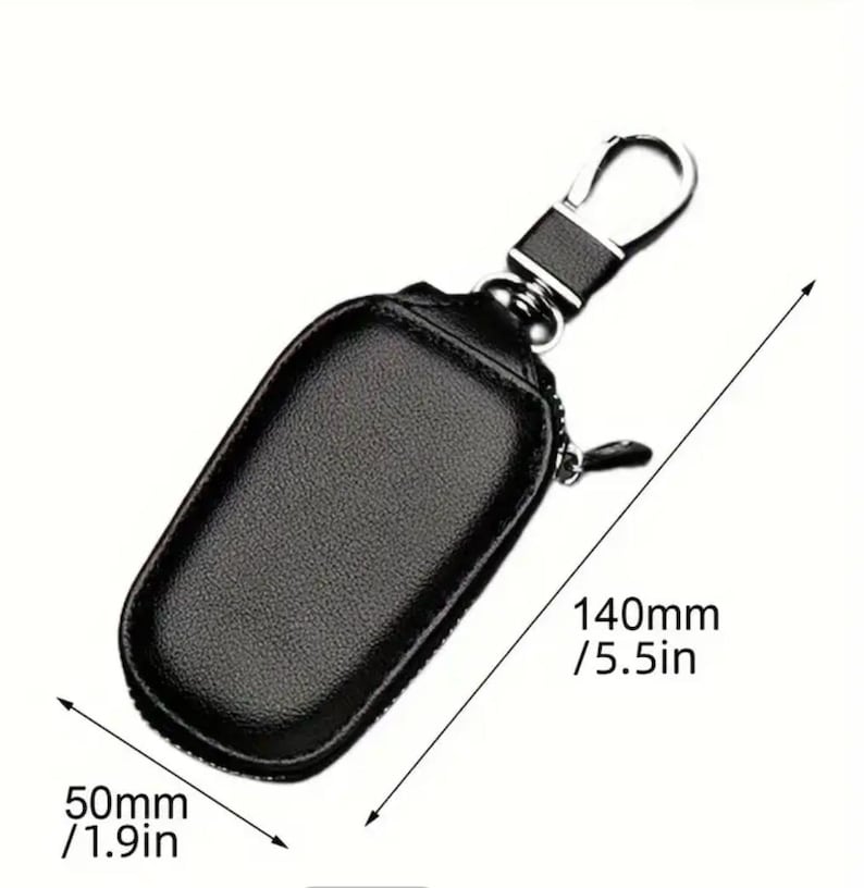 Puede incluir: Porta llaves de cuero negro con cierre de cremallera y gancho de metal plateado. El porta llaves mide 140 mm de largo y 50 mm de ancho.