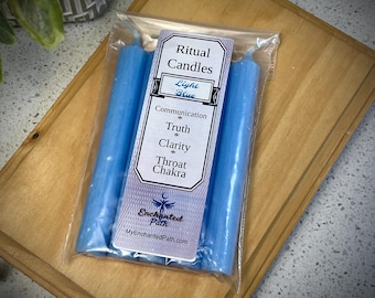 Pode incluir: Três velas rituais azuis claras em um saco de plástico transparente. O rótulo diz "Ritual Candles Light Blue Communication Truth Clarity Throat Chakra" e "Enchanted Path MyEnchantedPath.com"