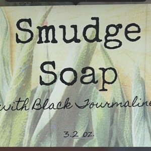 May include: A bar of soap with a green and white floral design. The label reads "Smudge Soap with Black Tourmaline" and "3.2 oz."