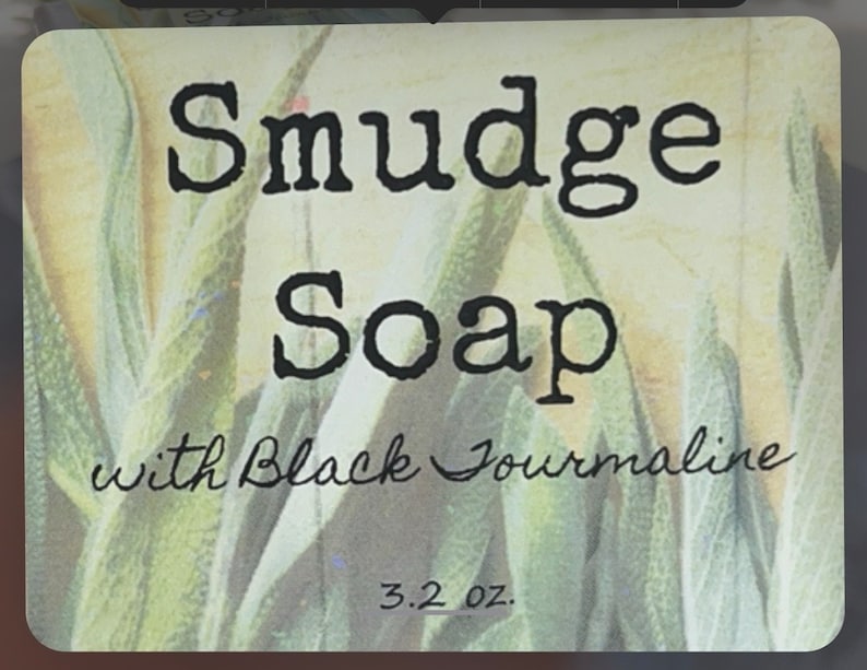 May include: A bar of soap with a green and white floral design. The label reads "Smudge Soap with Black Tourmaline" and "3.2 oz."