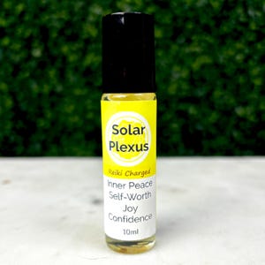 May include: A clear glass roll-on bottle with a black cap and a yellow label. The label reads "Solar Plexus" and lists "Reiki Charged" and other benefits. The bottle contains 10ml of liquid.
