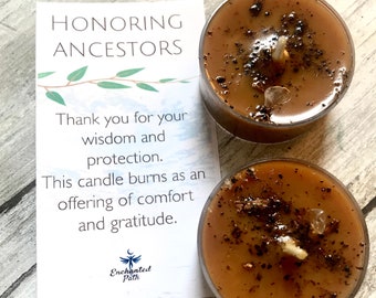 May include: Two brown tea light candles with a black and brown speckled wax surface. The candles are on a wooden surface with a white card that reads "Honoring Ancestors" and "Thank you for your wisdom and protection. This candle burns as an offering of comfort and gratitude. Enchanted Path."