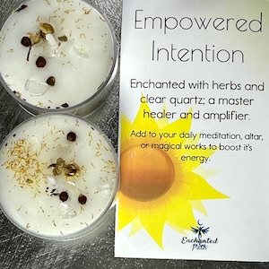 May include: Two white tea light candles with herbs and clear quartz crystals inside. The candles are labeled "Empowered Intention" and "Enchanted Path".