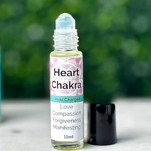 May include: A clear glass roll-on bottle with a light blue cap and a black cap next to it. The label reads "Heart Chakra" with the words "Reiki Charged, Love, Compassion, Forgiveness, Manifesting" and "10ml".