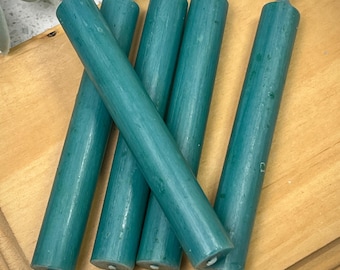 Pode incluir: Cinco velas de cor azul-esverdeada sobre uma superfície de madeira.
