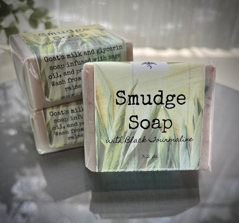 May include: Three bars of handmade soap with a green and white floral design. The label reads "Smudge Soap with Black Tourmaline 3.2 oz."