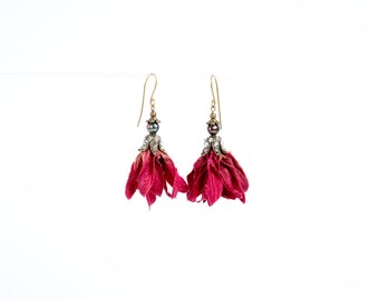 Puede incluir: Un par de pendientes colgantes con un diseño de flor rosa y un acento de perla. Los pendientes están hechos con flores secas y tienen un acabado dorado.