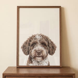 May include: A framed print featuring a detailed illustration of a dog's face. The dog has brown and white curly fur, with a focused gaze. The artwork is set in a dark brown wooden frame, creating a classic aesthetic. The background is a neutral beige.