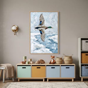 Textured winter mallard duck wall art above a storage unit with colorful bins, baskets, and wooden toys in a modern nursery.