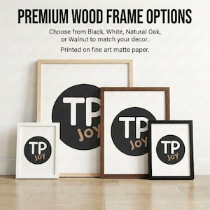 a collection of four framed artworks, each with a different wood frame color and size, arranged on a wooden floor against a white wall.