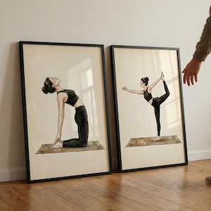 Könnte beinhalten: Zwei gerahmte Kunstdrucke mit Yoga-Posen. Jeder Druck zeigt eine Frau in schwarzer Kleidung, die eine Yoga-Pose auf einer gemusterten Matte ausführt. Die Rahmen sind schwarz und der Hintergrund ist ein neutrales Beige.