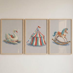 May include: Set of three framed prints featuring whimsical circus-themed illustrations. The prints depict a swan boat, a striped circus tent, and a rocking horse, all in soft pastel colors. The frames are made of light-colored wood.