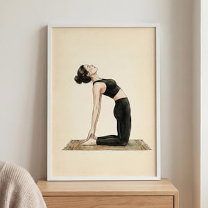 Könnte beinhalten: Ein gerahmter Aquarelldruck einer Person in einer Yoga-Pose. Die Person trägt einen schwarzen Sport-BH und Leggings, die sich auf einer kleinen Matte nach hinten beugt. Der Hintergrund ist hellbeige.