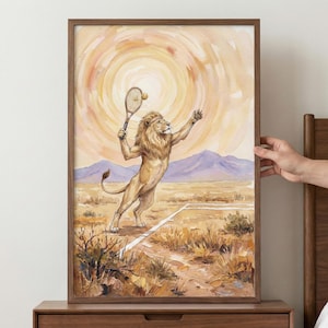 Pode incluir: Uma impressão em aquarela emoldurada retrata um leão jogando tênis. O leão, com uma juba dourada e uma faixa, está no meio do swing em uma quadra de tênis. O fundo apresenta um pôr do sol, montanhas e vegetação rasteira seca. A moldura é de madeira escura.