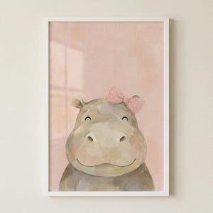 May include: A framed watercolor print of a smiling hippo with a pink bow. The hippo is painted in shades of gray and brown, set against a soft pink background. The artwork is in a white frame, suitable for a nursery or child's room.