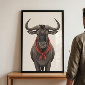 Puede incluir: Una lámina de arte enmarcada que presenta una ilustración estilizada de un ñu gris oscuro con grandes cuernos curvados. El animal se muestra desde el pecho hacia arriba, luciendo un pañuelo rojo brillante atado al cuello sobre un fondo crema.