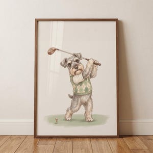 May include: A framed wall art print featuring a gray schnauzer dog wearing a light green and white argyle sweater vest. The dog is standing on a patch of green grass, holding a brown golf club over its shoulder, with a small golf tee nearby.