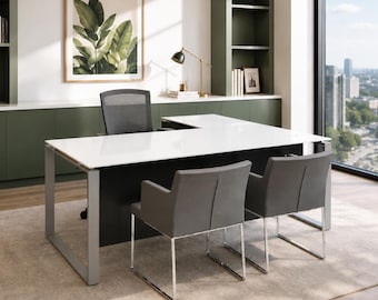Puede incluir: Un escritorio en forma de L con superficie blanca y base negra, que incluye una silla de oficina de malla negra y dos sillones tapizados en gris con bases de trineo cromadas, en un espacio de trabajo moderno con armarios verdes.