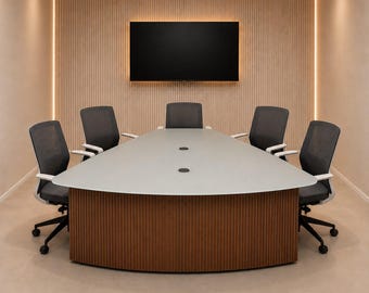 Puede incluir: Una sala de conferencias con una mesa triangular de color gris claro sobre una base de listones de madera oscura, rodeada por cinco sillas de oficina de malla negra. Una gran pantalla negra rectangular está montada en una pared de listones.