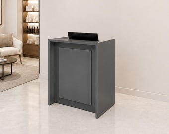 Puede incluir: Un mostrador de recepción gris oscuro con un panel frontal rectangular y una superficie superior plana. El escritorio tiene una construcción sólida y limpia con un acabado liso, diseñado como un mueble independiente para una oficina o vestíbulo.