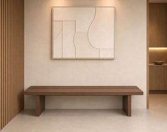 Puede incluir: Un banco rectangular de madera con asiento plano y dos soportes verticales sólidos. Sobre el banco cuelga una gran pieza de arte mural cuadrada de color blanco roto con líneas geométricas texturizadas en relieve y formas curvas.