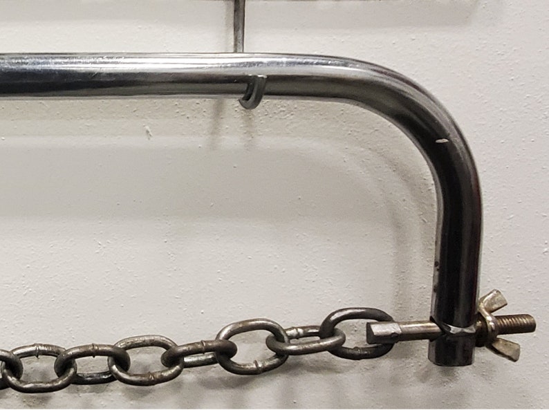 May include: A silver metal chain attached to a silver metal hook. The hook is attached to a silver metal bar.