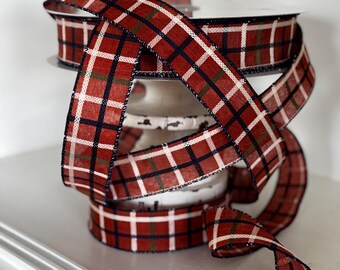 Peut inclure: Un rouleau de ruban à carreaux rouge avec des accents blancs, verts et marine. Le ruban est enroulé autour d'un support de bobine en métal blanc. Ce ruban décoratif est adapté aux travaux manuels, à l'emballage de cadeaux ou aux décorations de fêtes.
