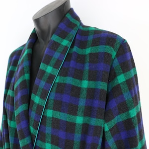 May include: A tartan dressing gown in green, blue, and black, shown on a mannequin. The robe has a traditional plaid design with a teal trim. The fabric looks to be a soft, woven material, suitable for lounging.