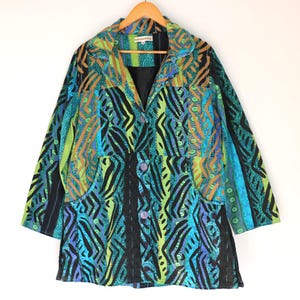 May include: A long-sleeved jacket featuring a vibrant patchwork pattern in shades of lime green, turquoise, blue, and black. The garment includes a notched collar, a button-front closure with three visible buttons, and two side pockets.