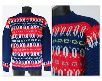 May include: A vintage blue, red, and white patterned sweater. The sweater features a crew neck and long sleeves. The design includes rows of geometric shapes and patterns in red, white, and blue. The sweater is displayed on a mannequin.