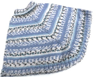 May include: A knitted blue poncho with a patterned design in white, black, and teal. The poncho has a ribbed collar and a scalloped edge. The overall design is symmetrical, with the pattern repeating across the fabric.