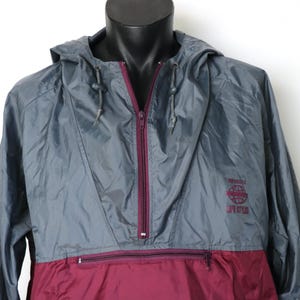 May include: A grey and burgundy hooded jacket with a zip fastening and a logo that says "Worldwide Lifestyle" on the right side of the chest.