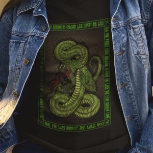 May include: A black t-shirt with a green snake graphic and the text "In darkness he crawls, like dust in the wind, and the less honest and wills you..."