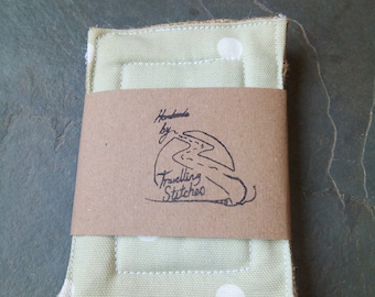 May include: Handmade by Travelling Stitches, a green and white polka dot fabric with a brown paper label. The label has a hand-drawn illustration of a road and the text "Handmade by Travelling Stitches".
