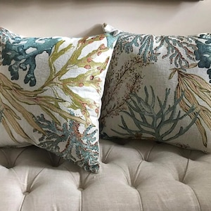 May include: Two decorative throw pillows with a white background and a blue, green, and brown sea life pattern.