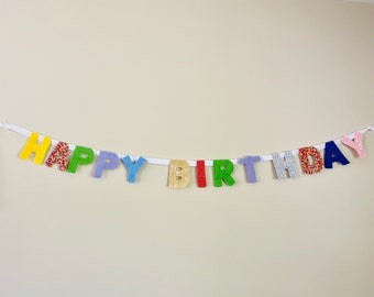 May include: A colorful felt banner with the words "Happy Birthday" in different colors and patterns.